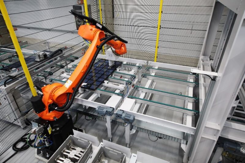 Roboter bewegt Solarmodul im Fertigungsumfeld.