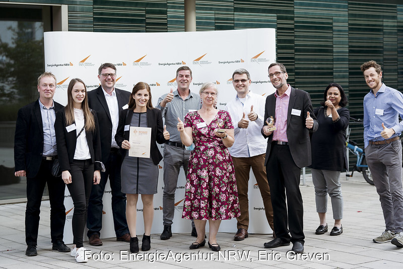 Preisträgerinnen und Preisträger freuen sich mit erhobenem Daumen vor einem Euroaolar-Transparent.