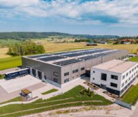 Eine Fabrik mit Solarmodulen auf dem Dach im malerischen Allgäu.