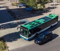 Luftbild eines parkenden Busses mit Solarmodulen im Dach.