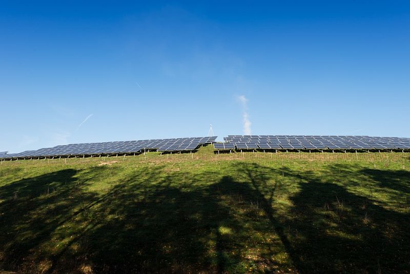 Ein Solarpark auf einem Hügel in der Ferne.