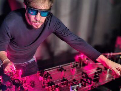 Ein Forscher mit Schutzbrille arbeitet bei rotem Licht an einer Apparatur.