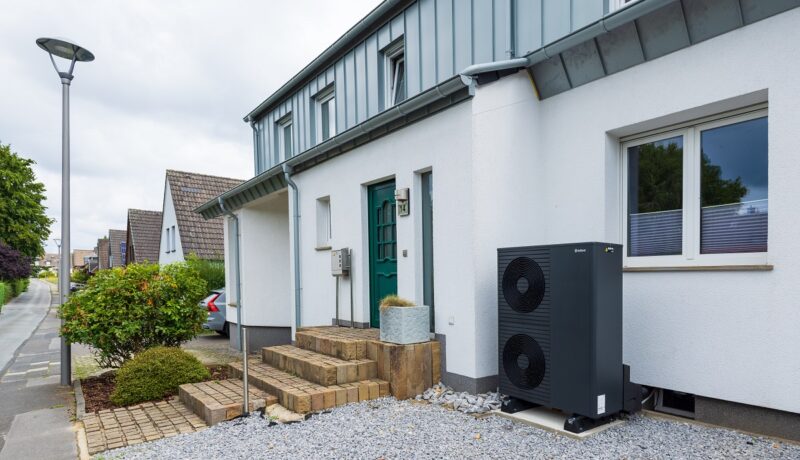 Die Außeneinheit der Wärmepumpe Arotherm plus von Vaillant vor einem Bestandsgebäude.