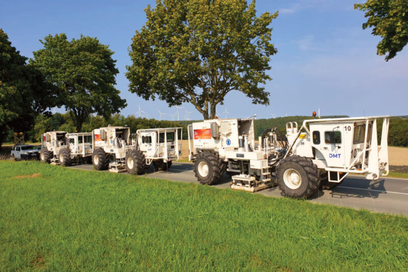 Mehrere Vibrotrucks auf einer Nebenstraße im Grünen