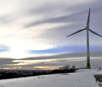 Windkraftwerk auf der ehemaligen Deponie in München-Fröttmaning mit Schnee und Sonnenuntergang