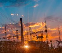 Sonnenuntergang hinter einer Trafostation und einem konventionellen Kraftwerk