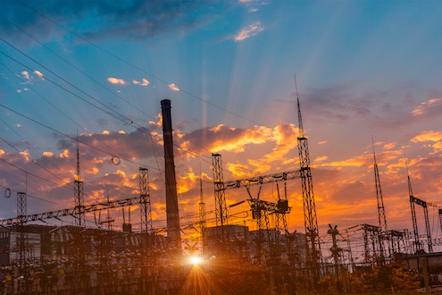 Sonnenuntergang hinter einer Trafostation und einem konventionellen Kraftwerk