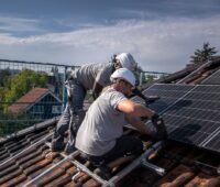 Zwei Handwerker installieren eine PV-Anlage auf einem Einfamilienhaus.